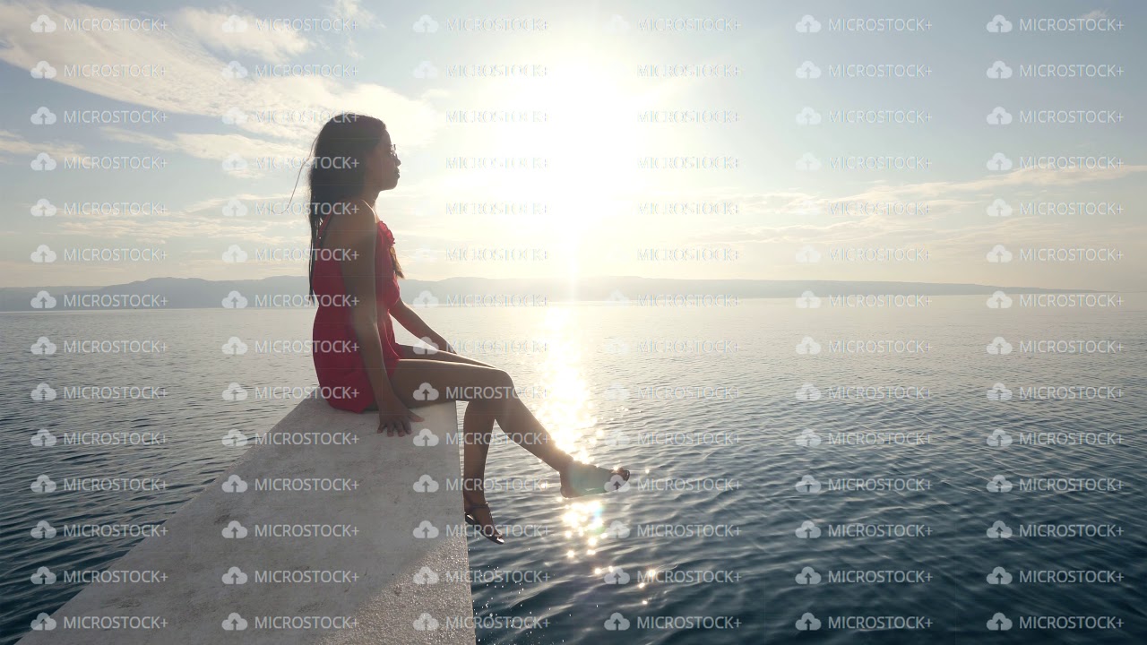 A young woman sitting on the edge of a boat with beautiful view of ...