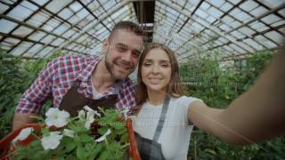 Cheerful Loving Couple Gardeners Taking Selfie Picture On Smartphone Camera And Kissing While
