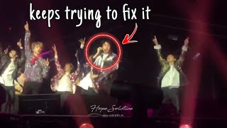 Hoseok tries to inform the staff of his mic issue while performing