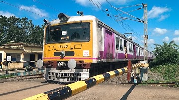 Newly painted shiny EMU local trains swiftly passing through a Level crossing