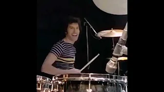 Freddie Mercury playing drums and Roger Taylor playing guitar