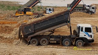 Building up land with dump trucks dumping dirt and shantui bulldozer pushing dirt​​ to flatten