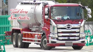 赤の大型タンクローリートラックが工事現場にバラセメントを運ぶ 