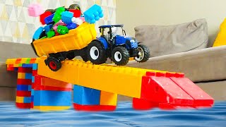 Через мост из блоков проезжают игрушечные машинки и тракторы