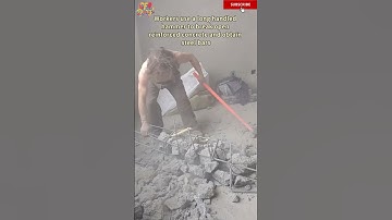 Workers use a long handled hammer to break open reinforced concrete and obtain steel bars