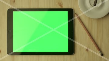 tablet with green screen laying on a wooden table in landscape mode Vy90OyjL