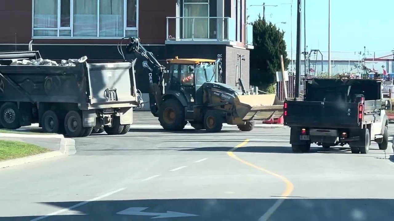 Small dump truck backing up and turning as well as a backhoe loader and a Mack dump truck