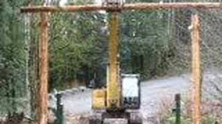 The excavator hoists the top log onto our front ranch entrance making us official!