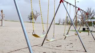 Stock Video - Empty swings moving in slow motion in the wind at a park in Texas