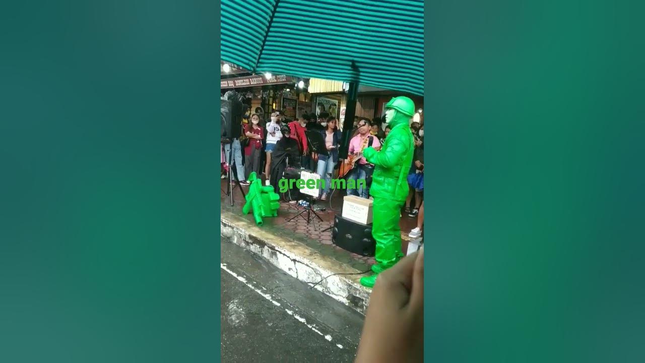 GREEN MAN singing on the sidewalk