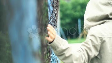 Woman In The Hood Walking By The Chain-Link Fence, Slow Motion Hd. Stock Footage