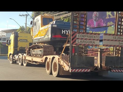 Carreta prata carregando máquina pesada
