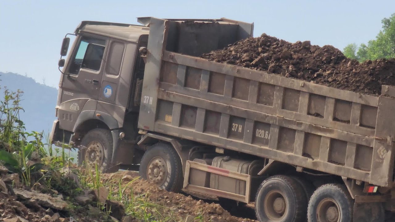 CAT D6R bulldozer, road roller, and Howo dump truck working together on road construction