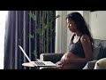 Young pregnant woman working at home touching her belly and talking to the baby