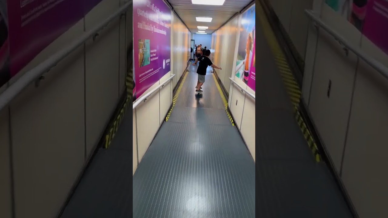 Boy rides RipStik skateboard down airplane walkway then falls forward and lands on floor