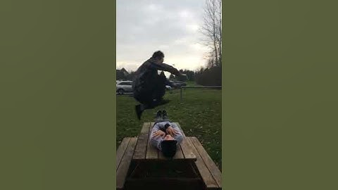Asian guy jumps over man on picnic table