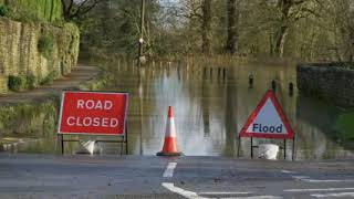 Long Shot of Road Closed and Flood Signs In Front of Flooded Street