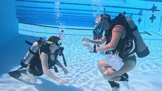Two Women Scuba Diving Playing Rock Paper Scissors.