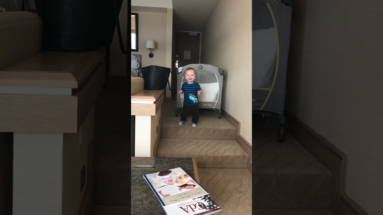 Little boyl walks down stairs then flips forward and bumps top of head on steps