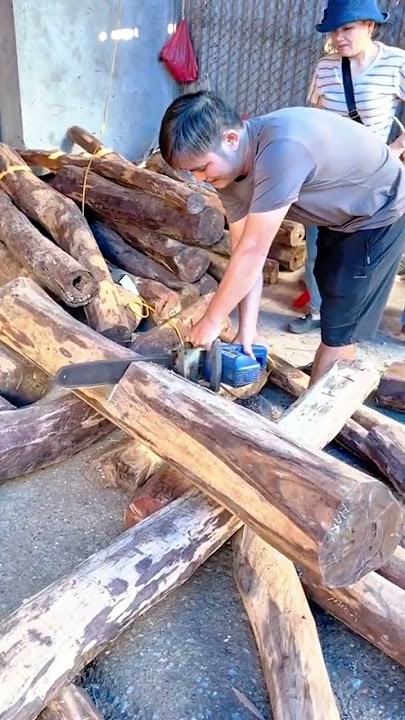 Worker cutting wooden logs using electric chainsaw tool