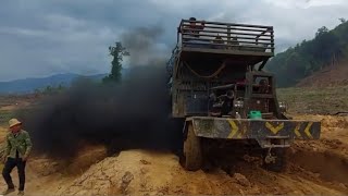 Three trucks were smoking in the middle of a muddy road