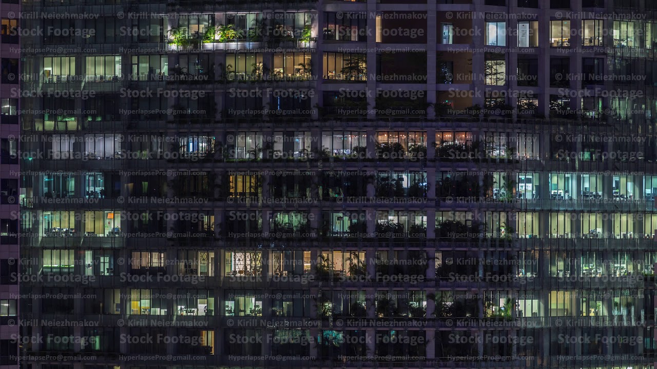Modern office building with big windows at night timelapse, in windows light shines