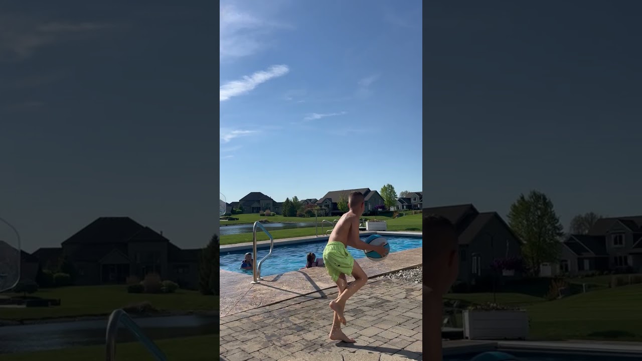 Boy climbs out of pool then shoot basketball at hoop then ball bounces off rim and hits him on head