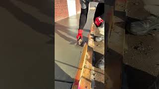 smoothing a long surface of fresh grey liquid cement using a professional silver metal trowel tool