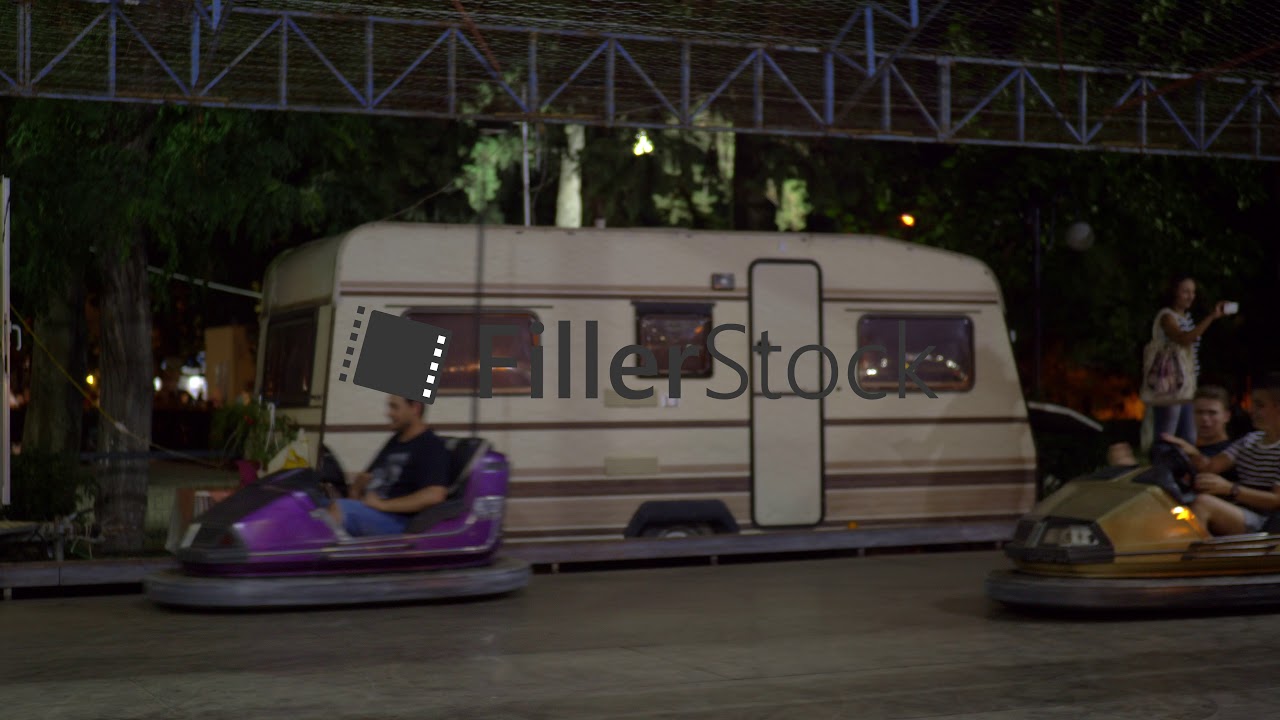 People on bumper cars attraction in outdoor amusement park