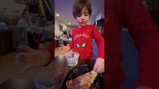 Boy puts parmesan cheese on his pizza then falls off chair and lands on floor in kitchen