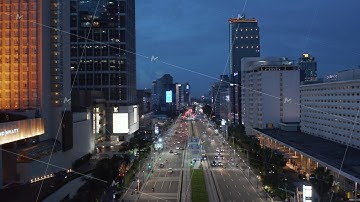 Aerial shot flying past Selamat Datang Monument in Jakarta towards multi lane highway through city