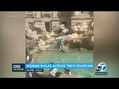 Tourist walks across Trevi Fountain in Rome to fill water bottle
