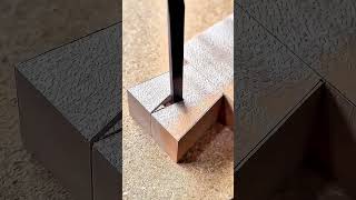 Chisel carves precise dovetail shoulder into clamped wooden workpiece