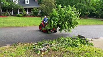 Kioti tractor moving tree limbs with Everything Attachment  grapple.