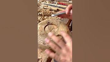 Carving a circular wooden bowl by hand using a curved chisel tool