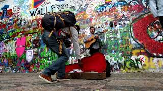 Street musician in Prague playing in front of the Lennon Wall