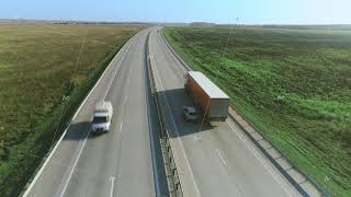 Trucks And Cars Drive Along The Highway. Aerial View On The Highway On A Sunny Day. Cargo