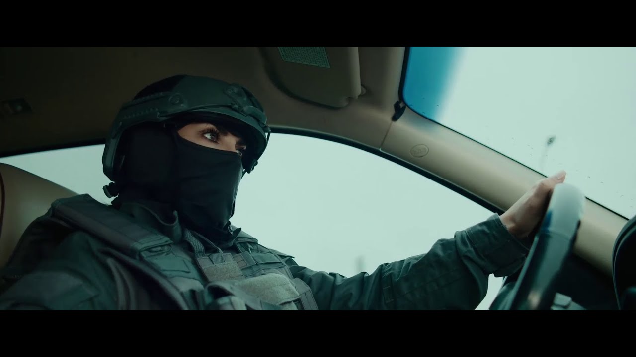 A masked female agent in tactical gear