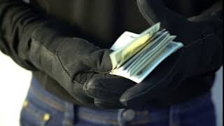 crime concept man in black leather gloves holding pile of money