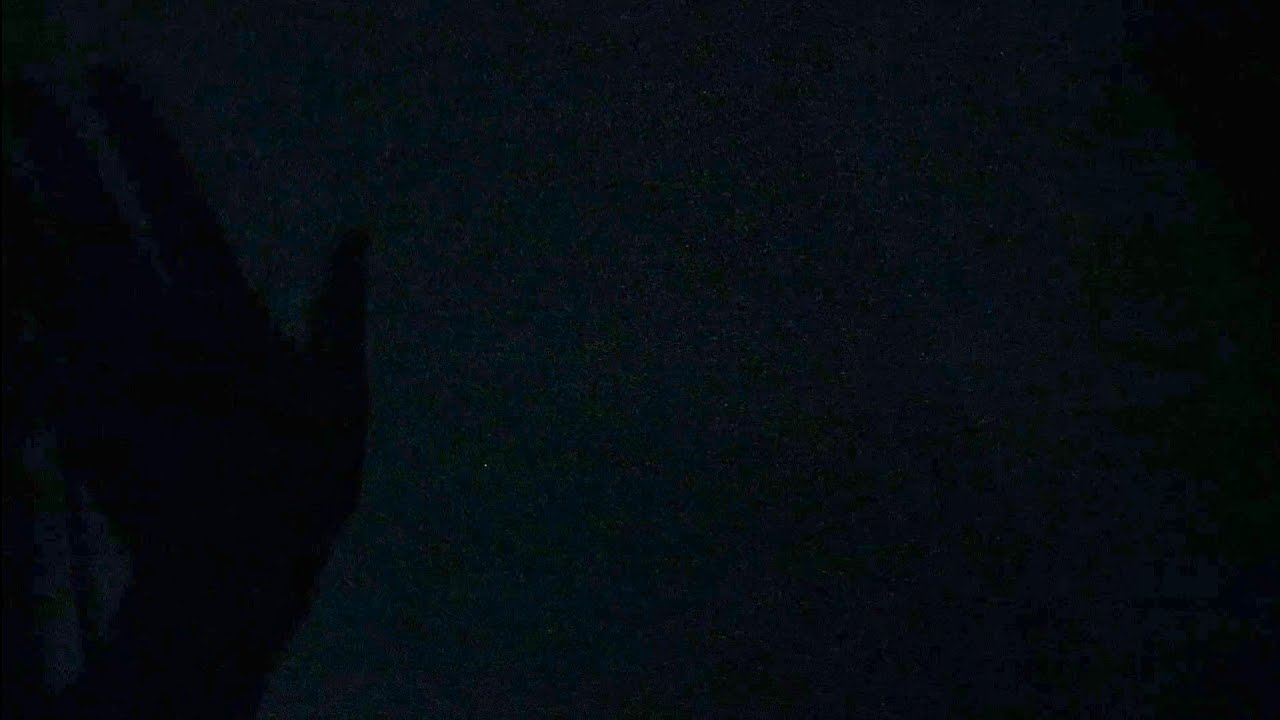 A hand moves mystically in the dark casting shadows on the wall