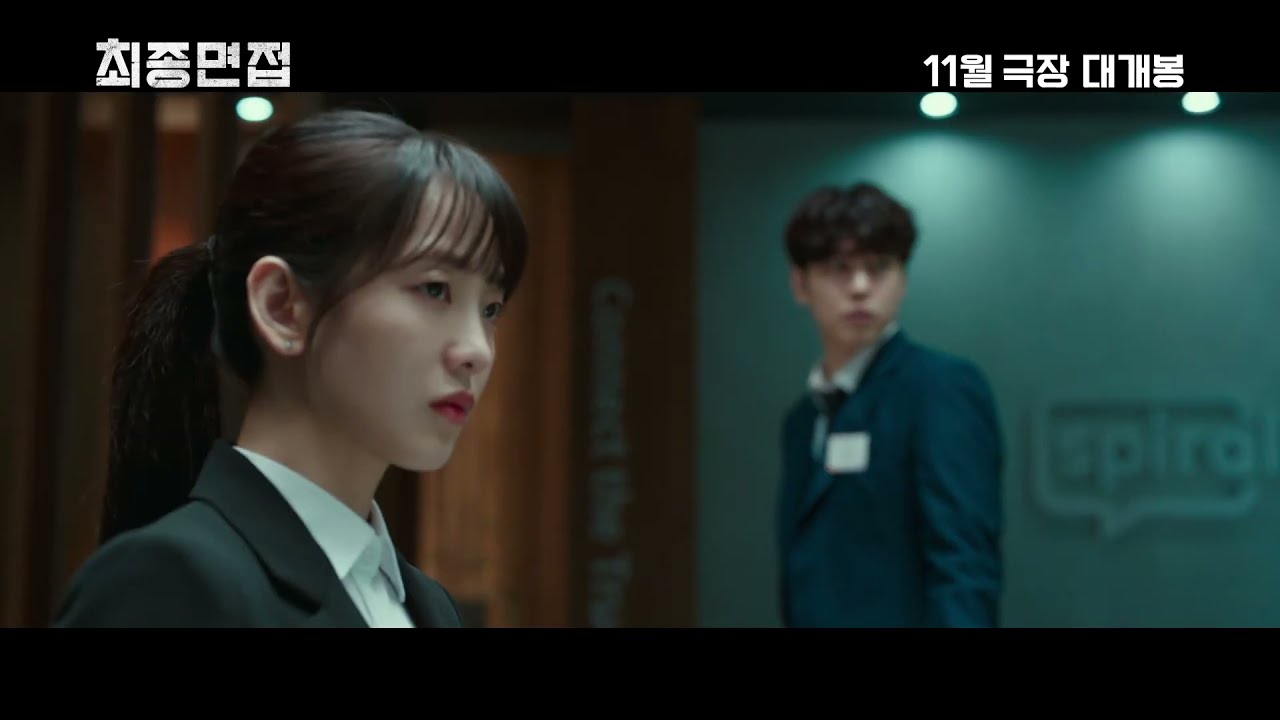 회의실에서 고개를 돌린 정장 차림 여성과 뒤에 선 남성