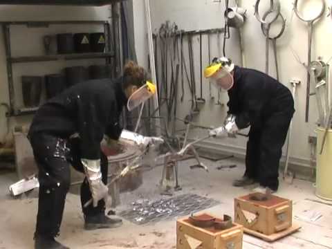 PART THREE - Sand Casting Process with Philip White and Jenny Dunseath in the foundry at Camberwell college of Art London. Video by Chris Follows part of the Process Arts Project - process.arts.ac.uk - University of the arts London Text Information supplied by Jenny Dunseath: 11. Take Cope off and set it aside. You should be able to see an imprint of your Pattern. Depending on its location use your hole-cutter and cut a Sprue hole by placing your hand on the back of the Cope and push hole cutter through the other side, twisting slightly. 12. Widen the Sprue hole on the top of the Cope, to enable the metal to flow. Ensure all edges are smoothed and there is no loose sand. 13. Tap on the Pattern to loosen, use a screw to take Pattern out. 14. With a set of Bellows blow out all loose sand, make sure everything is smooth. 15. Place your flask back together and pour your metal! 16. After pouring wait for the material to solidify. The amount of time this takes will depend on the size and density of the piece of metal you are creating. Large, dense pieces of metal will take more time to solidify than smaller pieces.
