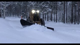 Tractor Snow Plowing yard and forest road  in Lappland.