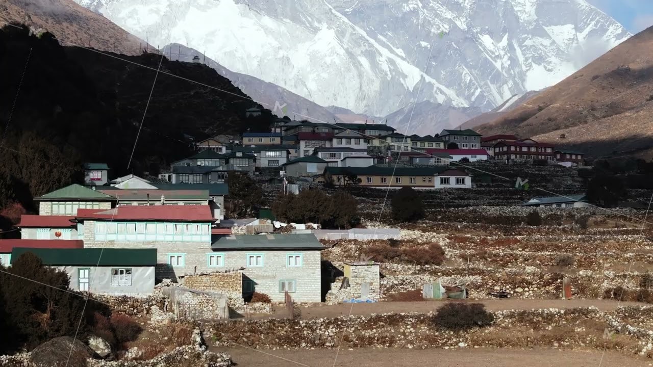 Skyward capture of a serene Himalayan settlement, featuring traditional homes and lofty snow-capped