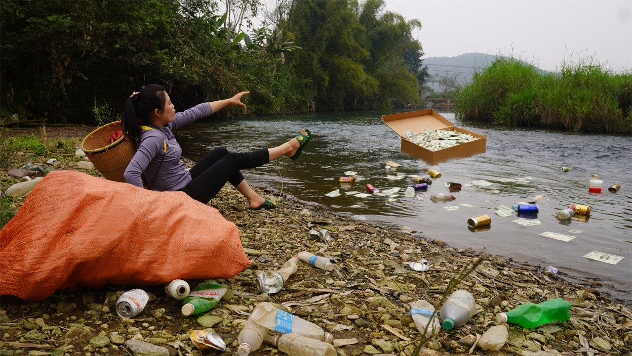 The girl retrieved a cardboard box containing a large sum of money that had drifted down the stream.