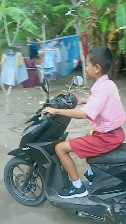 Anak SD belajar naik motor matic di halaman rumah