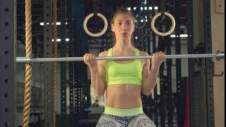 Girl Sitting in the Gym Doing Exercises For Biceps. Using Both Hands, Raises the Neck From the Bar