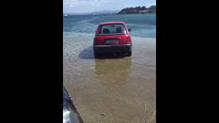 La grúa retira uno de los coches que la subida de marea cubrió en una rampa en A Pobra