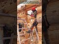 Découpe d'une ouverture dans une maison en rondins à l'aide d'une tronçonneuse et d'escabeaux