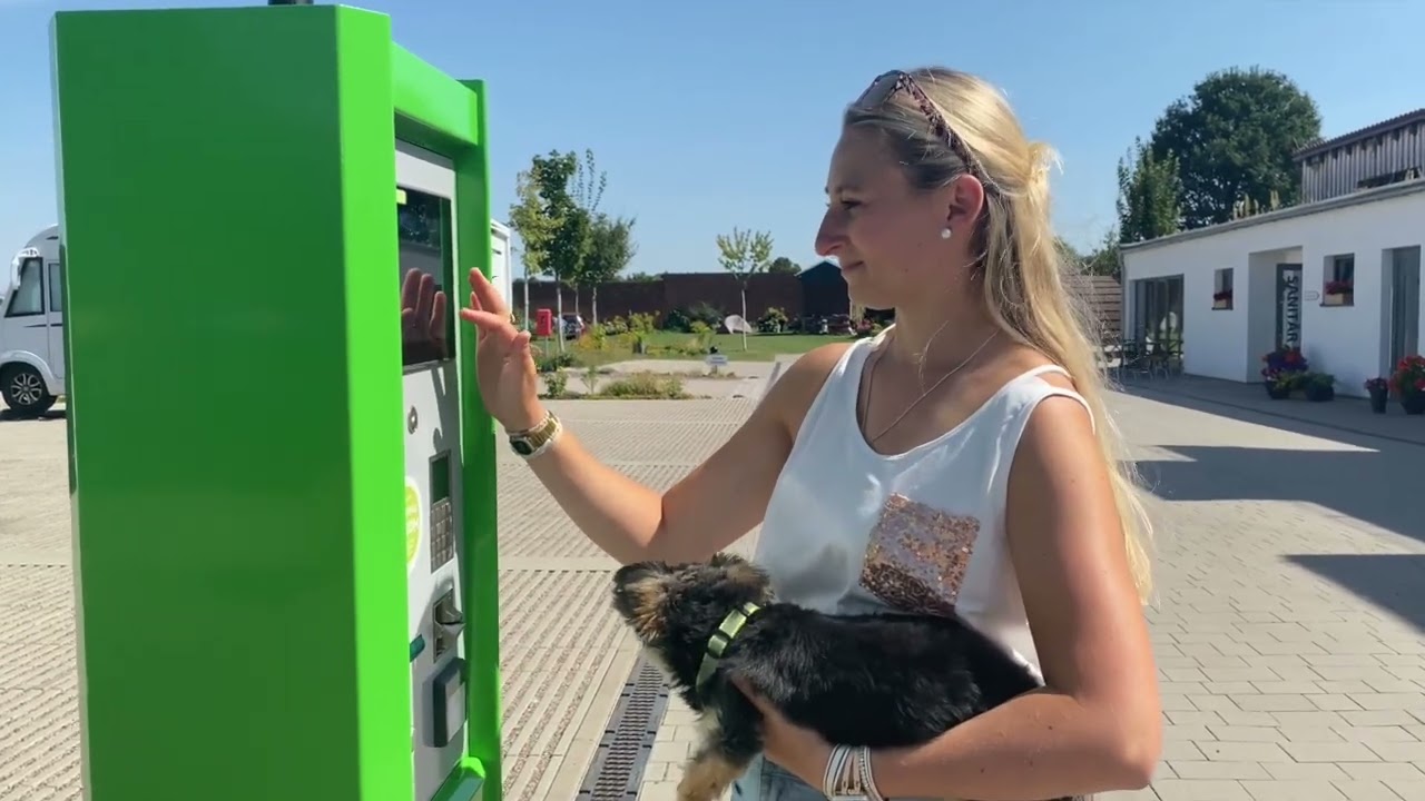Frau bedient den Camping-Strom Kassenautomat auf einem Campingplatz